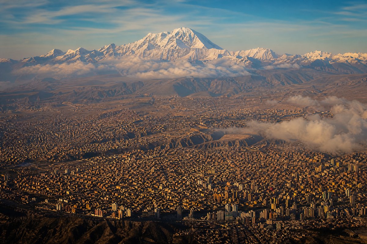 High-altitude city beneath dramatic snow-capped mountain range